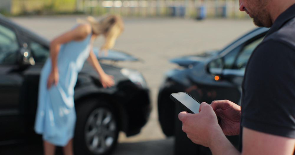 Szkoda parkingowa: Mężczyzna z telefonem, kobieta przy samochodzie.
